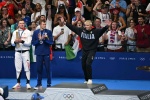 (L-R) Silver medallists Britain's Adam Peaty, US' Nic Fink and gold medallist Italy's Nicolo Martinenghi stand on the podium of the men's 100m breaststroke swimming event during the Paris 2024 Olympic Games at the Paris La Defense Arena in Nanterre, west 