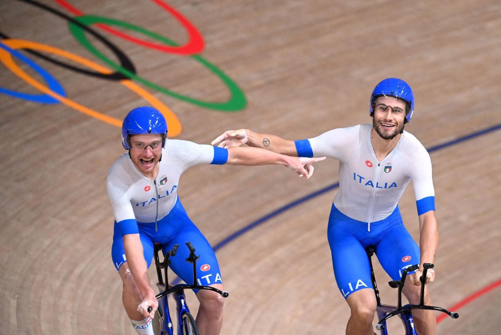 Italy's Simone Consonni (L) and Italy's Filippo Ganna celebrate after winning gold and setting a new World Record in the men's track cycling team pursuit finals during the Tokyo 2020 Olympic Games at Izu Velodrome in Izu, Japan, on August 4, 2021. (Photo 
